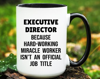 May include: White ceramic mug with a black interior and handle. The mug features the text "EXECUTIVE DIRECTOR BECAUSE HARD-WORKING MIRACLE WORKER ISN'T AN OFFICIAL JOB TITLE" in bold black letters.