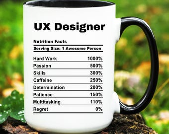 May include: White ceramic mug with a black handle. The mug has a black rim and features a graphic of a nutrition facts label with the title "UX Designer". The label lists various skills and attributes with percentages, including hard work, passion, skills, caffeine, determination, patience, multitasking, and regret.