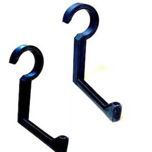 May include: Two black plastic hooks with a curved shape. The hooks are designed to hang items on a wall or other surface.