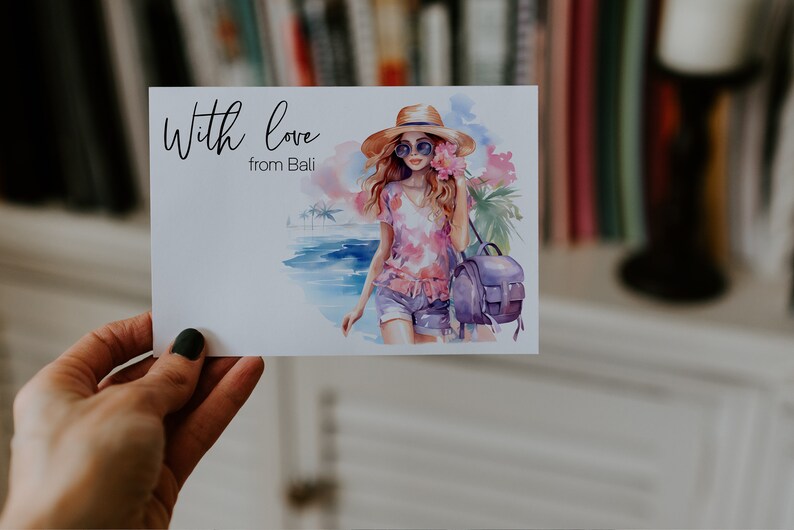 May include: A watercolour illustration of a woman wearing a straw hat, sunglasses, and a pink floral shirt. She is carrying a purple backpack and walking on a beach with palm trees in the background. The text "With love from Bali" is written on the card.