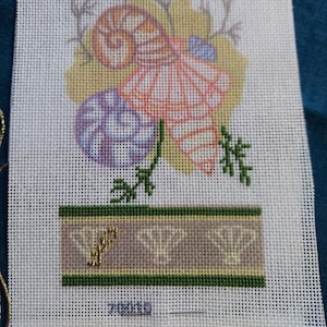 May include: A white canvas with a printed design of seashells and greenery. The design features a large seashell with a pink and orange color scheme, a smaller seashell with a blue and purple color scheme, and a brown seashell. The design is surrounded by green leaves and branches.