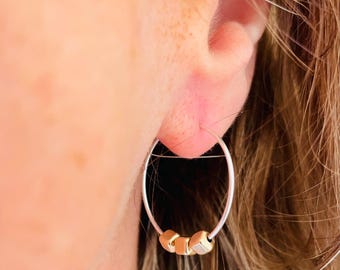 May include: Silver hoop earrings with three gold cube beads.