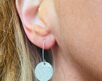 May include: Silver dangle earrings with a textured round disc pendant.