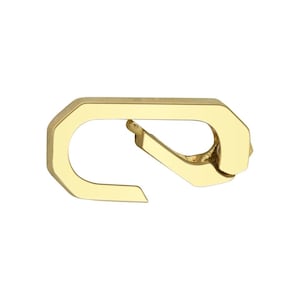Puede incluir: Un cierre dorado en forma octogonal con un brazo curvo articulado. El cierre está diseñado para abrirse y cerrarse, probablemente para asegurar objetos. El metal tiene un acabado pulido que refleja la luz.
