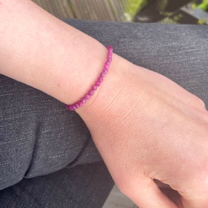 May include: A pink gemstone bracelet with small round beads.