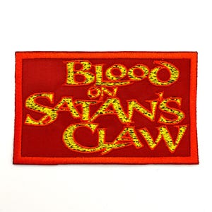 May include: A rectangular red patch with the words "Blood on Satan's Claw" embroidered in yellow and black. The patch has a red border and is likely designed to be sewn onto clothing or accessories.
