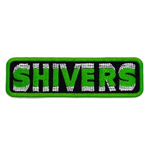 May include: Embroidered patch featuring the word "SHIVERS" in vivid green, outlined in white, set against a black backdrop. The patch has a green border and a rectangular form. The text is in a bold, sans-serif font.