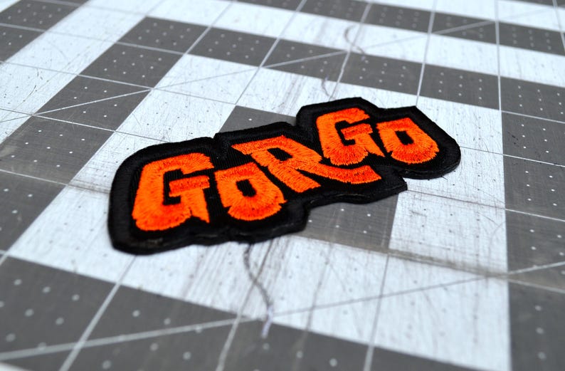 Close up detail of an orange and black embroidered logo patch for the classic Kaiju monster movie Gorgo.