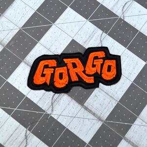 Orange and black embroidered logo patch for the classic Kaiju monster movie Gorgo.