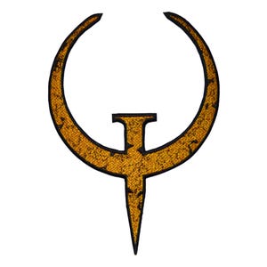 Puede incluir: Un parche bordado con el logotipo de Quake, una letra Q estilizada con forma de media luna y un clavo vertical en el centro. El diseño tiene un acabado dorado metálico texturizado con un borde negro y detalles interiores en negro.