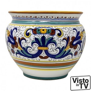 Op de afbeelding: Een grote, witte keramische pot met een ronde, brede basis en een licht uitlopende rand. De pot is versierd met een kleurrijk bloemenpatroon in tinten blauw, groen, geel en rood. Het patroon bevat ingewikkelde spiralen en bladeren.