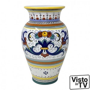May include: A white ceramic vase with a blue and yellow floral design. The vase has a wide mouth and a narrow base.