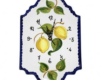 May include: White ceramic clock with blue trim and a lemon design. The clock face has black Roman numerals and black hands.
