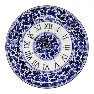 May include: A white ceramic clock with blue floral designs and Roman numeral markings. The clock face has a smaller blue floral design in the center.