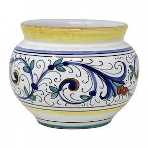 Könnte beinhalten: Ein weißer Keramiktopf mit gelbem Rand und blauen und grünen Blumenmustern. Der Topf hat eine runde Form und eine leicht ausgestellte Lippe.