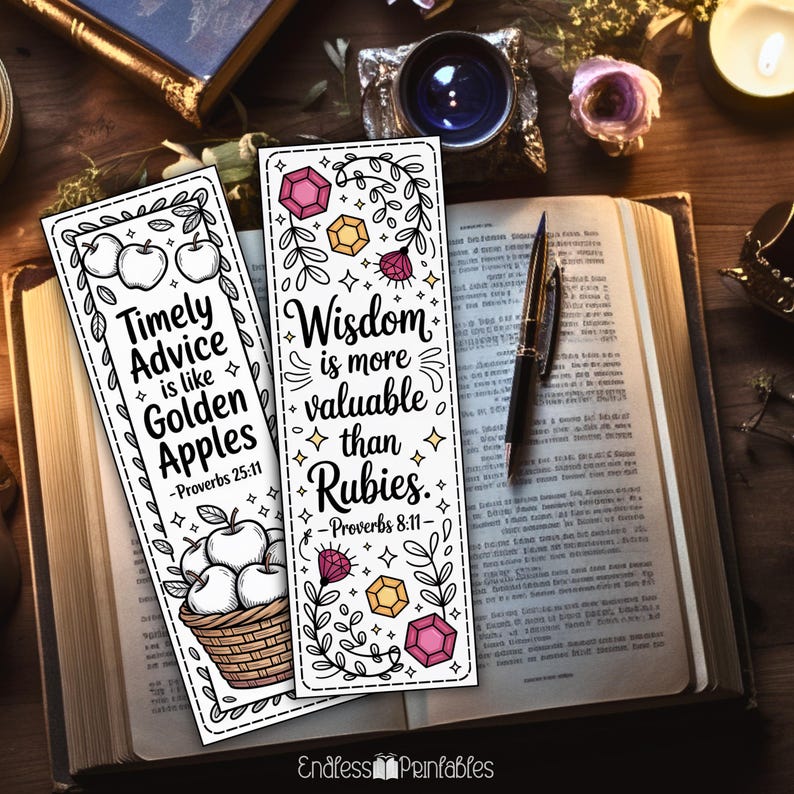 Op de afbeelding: Twee witte bladwijzers met zwarte tekst en illustraties liggen op een open boek. E&eacute;n bladwijzer leest "Timely Advice is like Golden Apples" met appelillustraties. De andere zegt "Wisdom is more valuable than Rubies" met edelsteenillustraties.