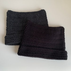 May include: Two crocheted hats, one in dark gray and one in black.