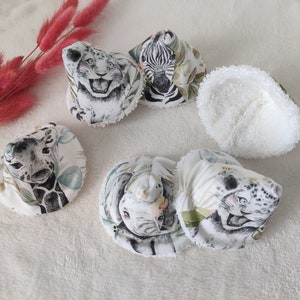 Peut inclure: Cinq langes en coton blanc avec différents motifs d'animaux. Les motifs comprennent un zèbre, une girafe, un lion et deux éléphants. Les langes ont un dos en tissu éponge blanc.