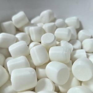 May include: A close-up shot of a bowl filled with white marshmallows. The marshmallows are cylindrical with rounded edges and a soft, fluffy appearance. They are piled together, filling the frame.