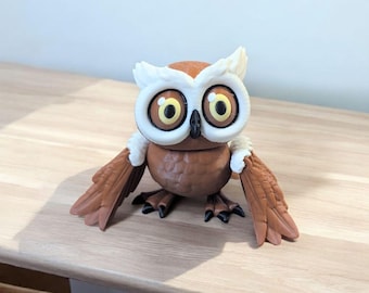 May include: A brown owl figurine with large, yellow eyes and white feathers around its head. The owl has brown wings and is standing on a wooden surface.