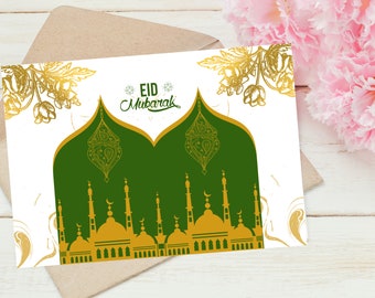 Puede incluir: Tarjeta de felicitación con un diseño de mezquita verde y dorada, con las palabras "Eid Mubarak". La tarjeta está sobre un fondo blanco, con detalles florales dorados y un sobre marrón. Hay flores rosas en el fondo.