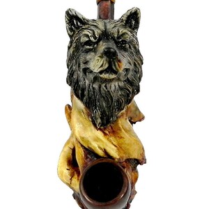May include: A wooden smoking pipe with a wolf head design. The wolf is brown and black with a yellow and brown wooden base. The pipe bowl is brown.
