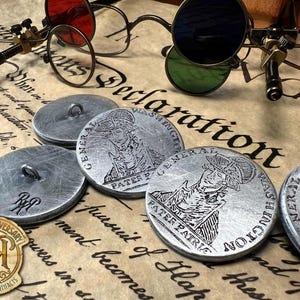 May include: A collection of round silver-toned metal buttons featuring an embossed portrait of George Washington with the text General Washington and Pater Patriae. The buttons have a central loop on the back and a stamped RR logo on some.