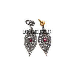 May include: Two silver leaf-shaped pendants with a red gemstone in the center, surrounded by small diamonds. The pendants are on a white background. "JAIPUR WHOLESELLER" is written in black text below the pendants.
