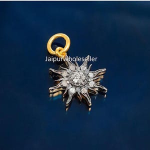 May include: A sun-shaped pendant with a gold loop and a silver sunburst design. The centre of the sun is filled with small, sparkling stones. The text "Jaipurwholeseller" is visible.