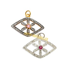May include: Two eye-shaped pendants. One is gold-toned with a flower design and a pink center stone, surrounded by small, clear stones. The other is silver-toned with a flower design and a red center stone, also surrounded by small, clear stones.