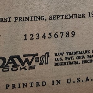 May include: A close-up of a book page with text. The text includes "FIRST PRINTING, SEPTEMBER 1980" and "DAW BOOKS". Numbers 1 to 9 are printed below. The text "PRINTED IN U.S.A." is at the bottom of the page.