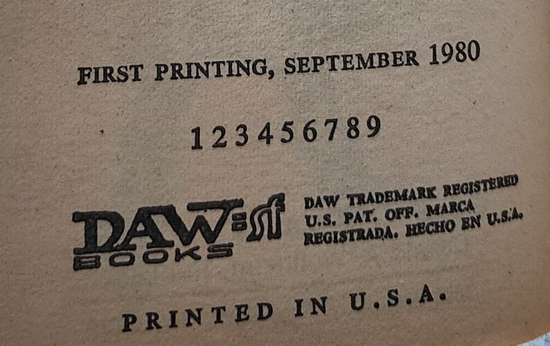 May include: A close-up of a book page with text. The text includes "FIRST PRINTING, SEPTEMBER 1980" and "DAW BOOKS". Numbers 1 to 9 are printed below. The text "PRINTED IN U.S.A." is at the bottom of the page.