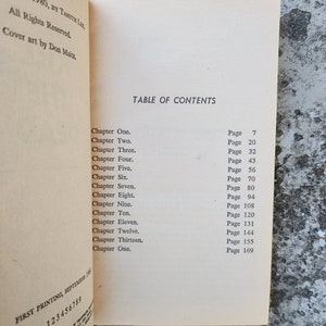 May include: An open book displaying a table of contents with chapter titles and page numbers. The book's title is not visible. The text includes "Chapter One" through "Chapter Thirteen". Printed in the USA.