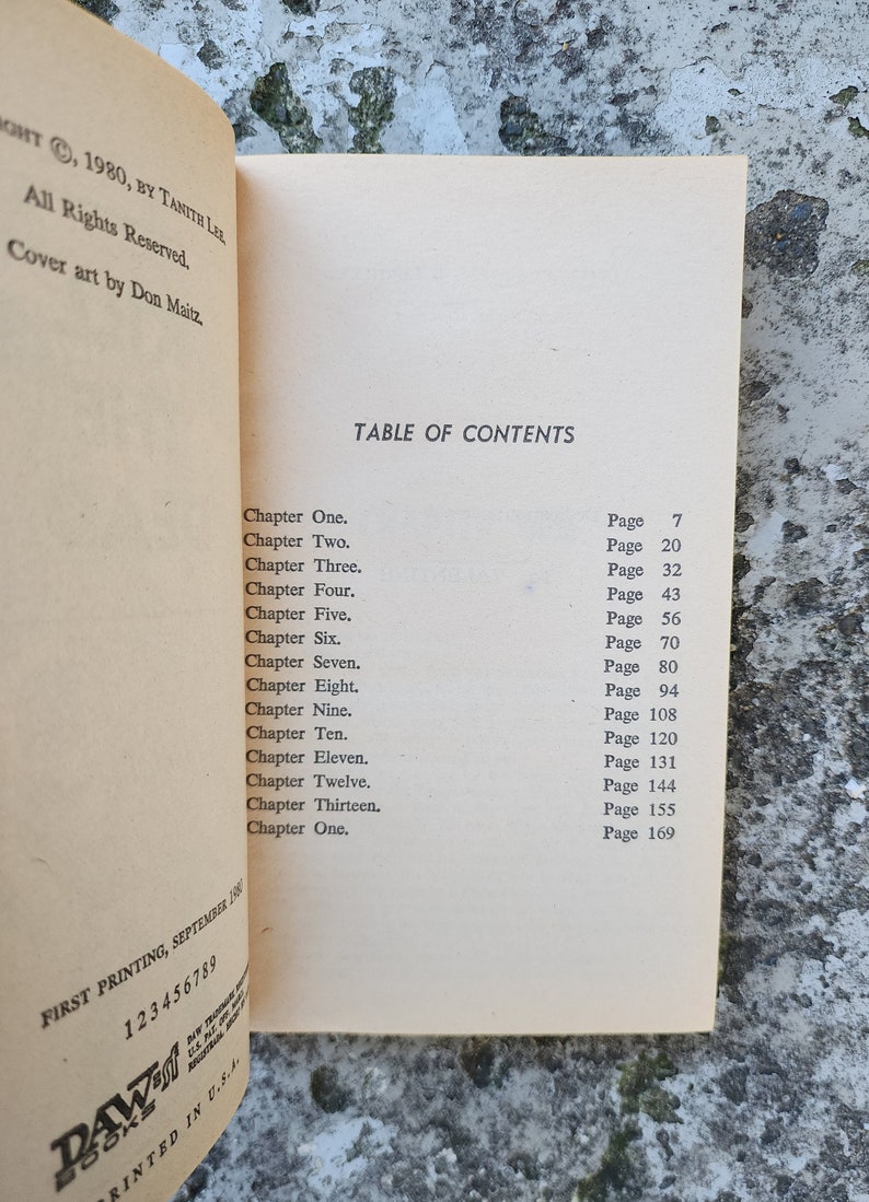 May include: An open book displaying a table of contents with chapter titles and page numbers. The book's title is not visible. The text includes "Chapter One" through "Chapter Thirteen". Printed in the USA.