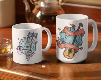 May include: Two white ceramic mugs with a Dungeons and Dragons theme. One mug features a green twenty-sided die with a hammer and the text "Mind if I lay on hands". The other mug features a green twenty-sided die with a lute and the text "You're my inspiration".