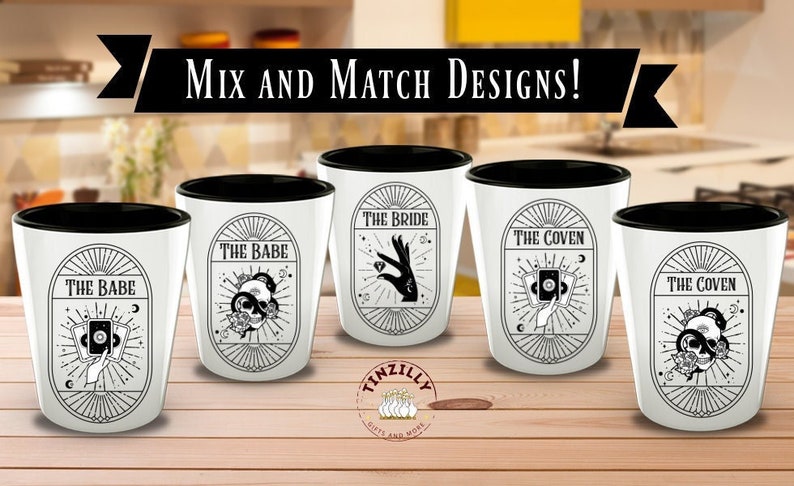 Op de afbeelding: Vijf shotglazen met zwarte randen en witte binnenkant. Elk glas heeft een ander ontwerp met zwart-wit illustraties. De ontwerpen omvatten "The Babe", "The Bride" en "The Coven".
