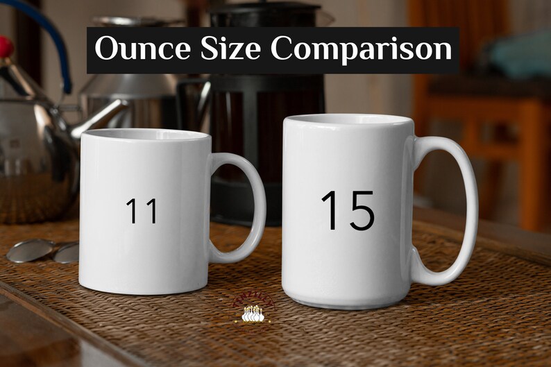 May include: Two white ceramic mugs with black numbers on them. The mug on the left says "11" and the mug on the right says "15". The mugs are on a brown wicker surface.