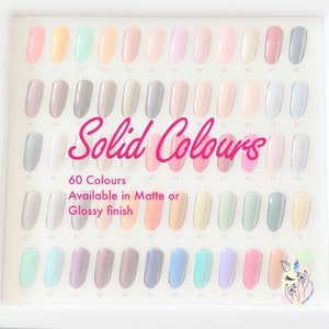 Puede incluir: Una carta de colores con 60 colores diferentes de esmalte de uñas en una bandeja blanca. Los colores están dispuestos en filas y columnas. El texto "Solid Colours" está escrito en letras rosas en la parte superior de la carta. El texto "60 Colours" está escrito en letras negras debajo de la carta. El texto "Available in Matte or Glossy finish" está escrito en letras negras debajo del texto "60 Colours".