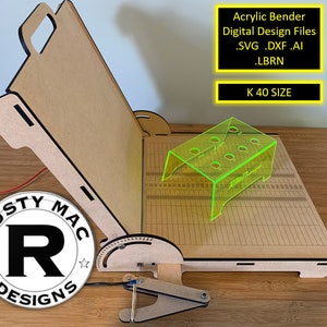 Może przedstawiać: Drewniany giętarka akrylowa z zielonym akrylowym elementem na górze. Giętarka jest oznaczona jako "Rusty Mac Designs" i "K 40 SIZE". Giętarka jest przeznaczona do gięcia arkuszy akrylowych.
