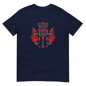 May include: A navy blue short-sleeve t-shirt featuring a central graphic of a thistle plant. The thistle design is filled with a red, yellow, and green plaid tartan pattern, showcasing sharp, pointed leaves and a textured, spiky flower head.