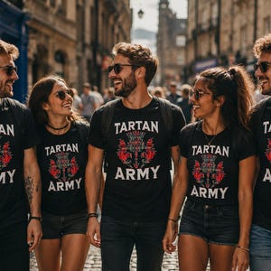 May include: A group of people wearing black t-shirts with the words "TARTAN ARMY" in white and a red and green thistle design. They are smiling and walking down a street.