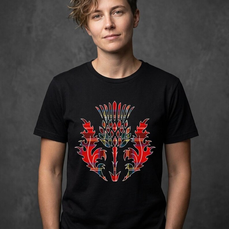 May include: A black short-sleeved t-shirt featuring a central graphic of a thistle plant. The thistle design is filled with a red, yellow, and blue plaid tartan pattern, showcasing sharp, flame-like leaf edges and a textured, rounded flower head.