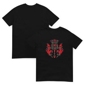 May include: A black short-sleeved t-shirt featuring a graphic of a thistle on the front. The thistle design is filled with a red, blue, and yellow plaid tartan pattern. The back of the t-shirt is plain black, showing a simple crew neck design.