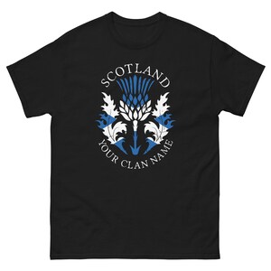 May include: Black t-shirt with a white graphic of a Scottish thistle with the words "Scotland" above and "Your Clan Name" below.