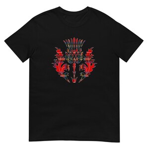 May include: A black short-sleeve t-shirt featuring a central graphic of a thistle plant. The thistle design is filled with a red, blue, and yellow plaid tartan pattern, showcasing sharp, jagged leaf edges and a detailed, segmented flower head.