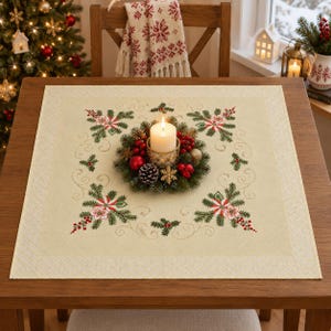 May include: A square cream-coloured table topper featuring embroidered green pine branches, red berries, and white flowers in each corner. A circular holiday wreath with a central white pillar candle sits in the middle of the fabric.