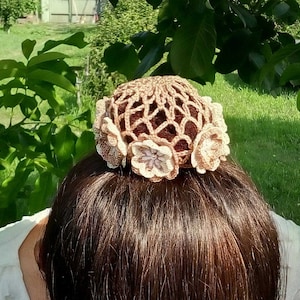 May include: A brown crocheted hair bun cover with beige flower accents.