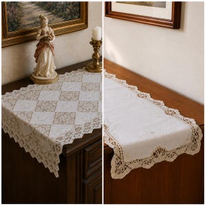 May include: A rectangular table runner featuring a white and beige diamond-patterned fabric with intricate lace trim along the edges. The runner displays a central section of alternating solid white and floral-patterned beige squares.