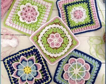 May include: Five crocheted squares with floral designs in shades of pink, green, blue, and white. The squares are arranged on a white wooden surface.