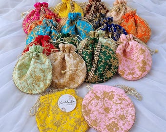 May include: A collection of round drawstring pouches in various colours including yellow, pink, green, blue, orange, and red. Each pouch features intricate gold floral embroidery and a beaded drawstring cord. One yellow pouch displays a circular tag with the text Vividluster.